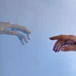 Persona extendiendo la mano hacia un robot, representando la colaboración entre humanos y agentes de IA autónomos