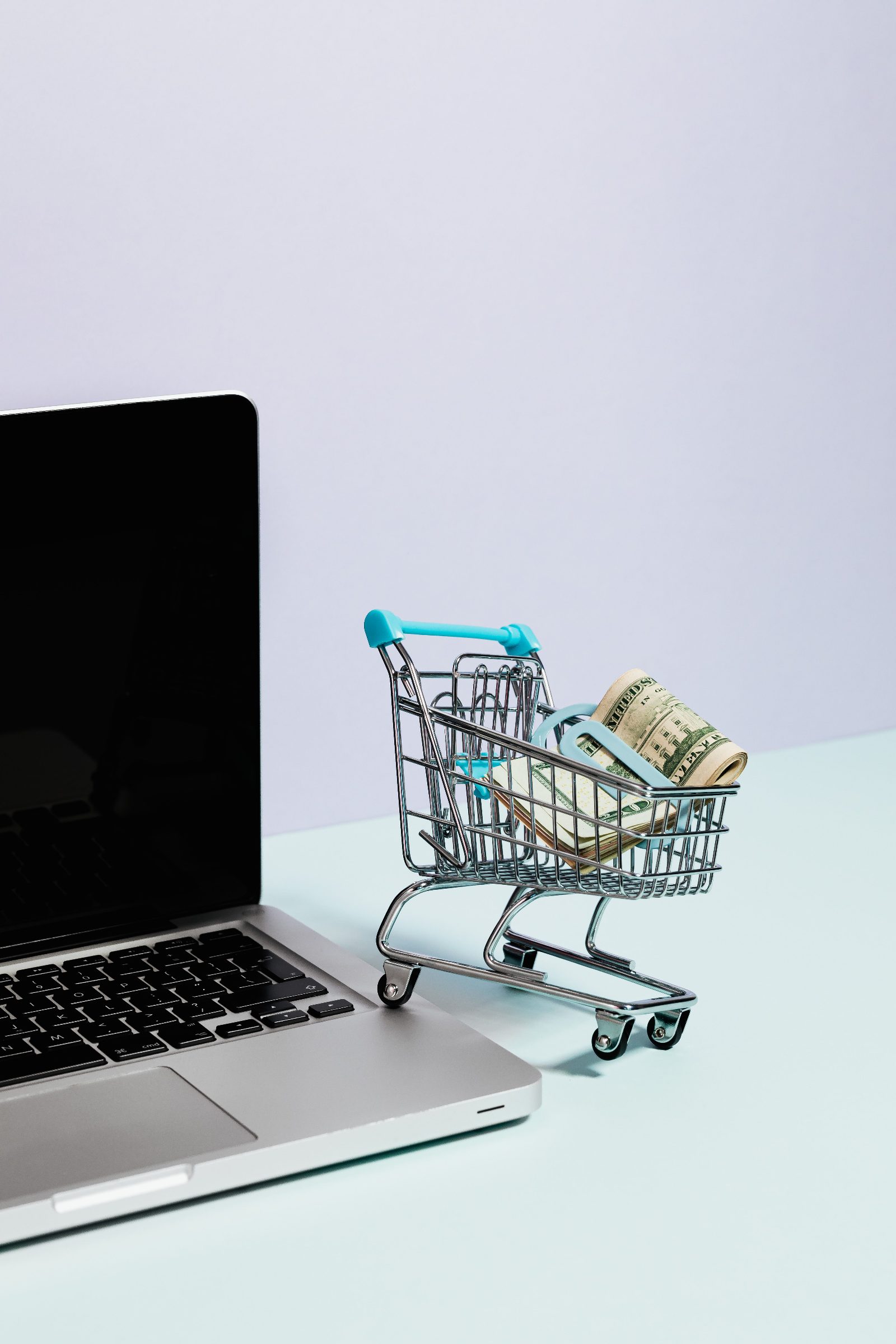 Carrito de compra con dinero sobre un portátil, representando precios dinámicos en ecommerce con inteligencia artificial