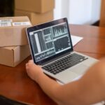 Persona analizando gráficos de datos en un portátil en un pequeño negocio, representando la baja adopción de IA en pymes españolas