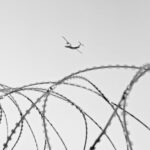 Helicóptero de vigilancia sobre valla fronteriza con alambre de espino, representando el control fronterizo en Ceuta y Melilla
