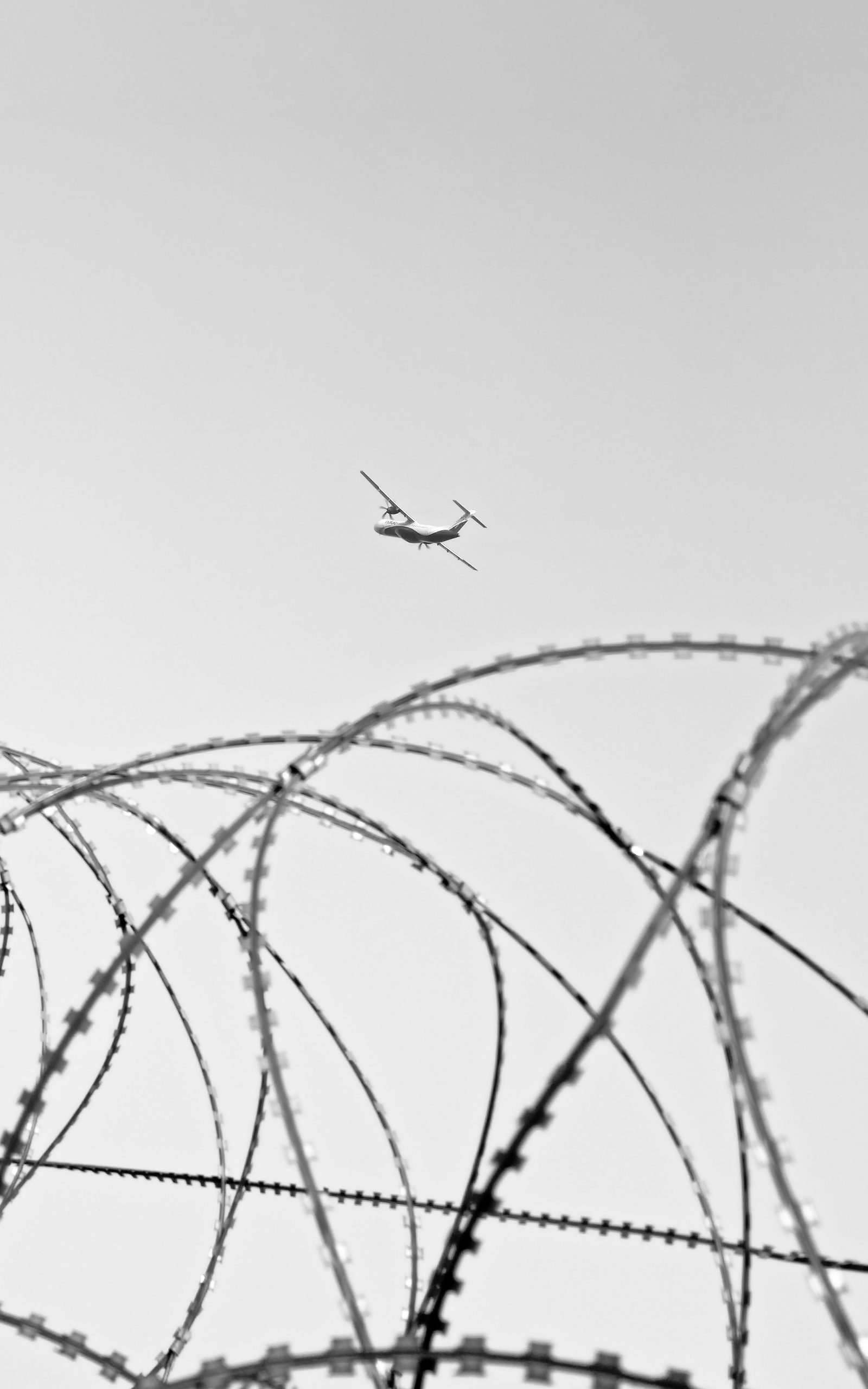 Helicóptero de vigilancia sobre valla fronteriza con alambre de espino, representando el control fronterizo en Ceuta y Melilla